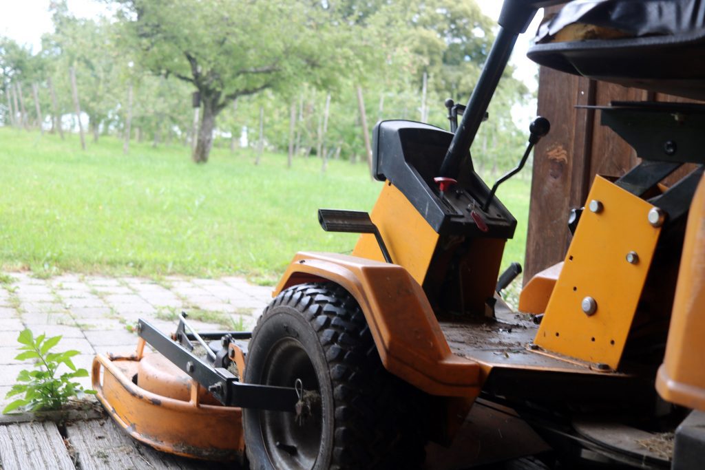image looking at side of lawn mower and overlooking unkept yard