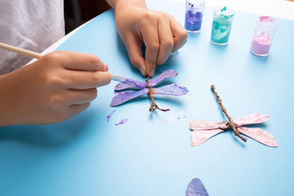 child crafting dragonfly from natural materials