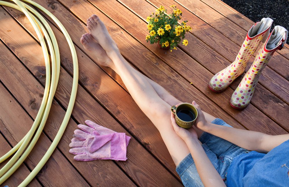 woman sitting on her deck, drinking coffee after doing yard work